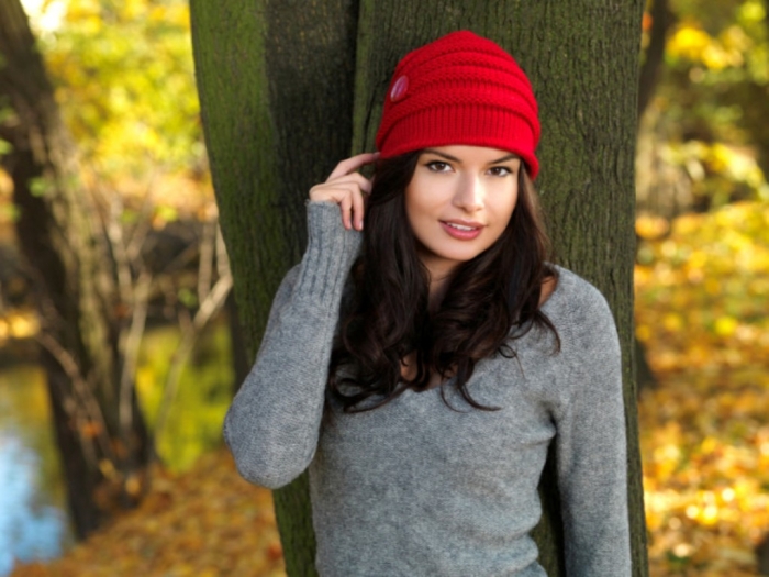 Smiling-brunette-wearing-red-beanie-hat-fall-scene-700x525