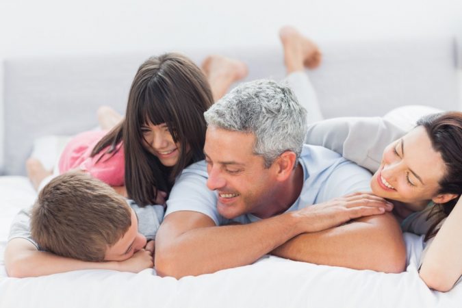 Cute family lying on bed and talking together at home