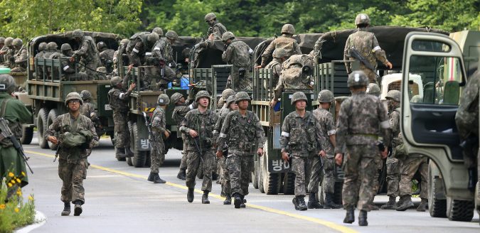 South Korean army soldiers exit their military trucks during an arrest operation in Goseong, South Korea, Monday, June 23, 2014. The parents of a runaway South Korean soldier suspected of killing five comrades at an outpost near the tense border with North Korea pleaded with him to surrender Monday as the military were besieging him and trying to capture him alive, officials said.(AP Photo/Yonhap, Hwang Kwang-mo) KOREA OUT