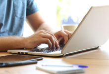 Man hands typing on a laptop keyboard on a desk