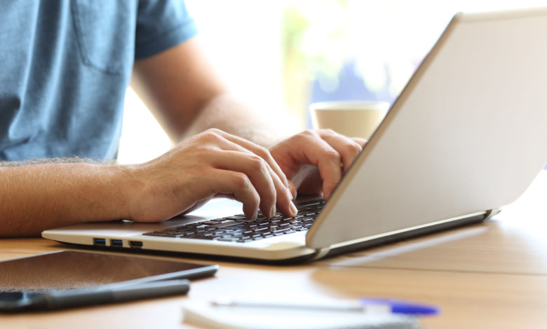 Man hands typing on a laptop keyboard on a desk